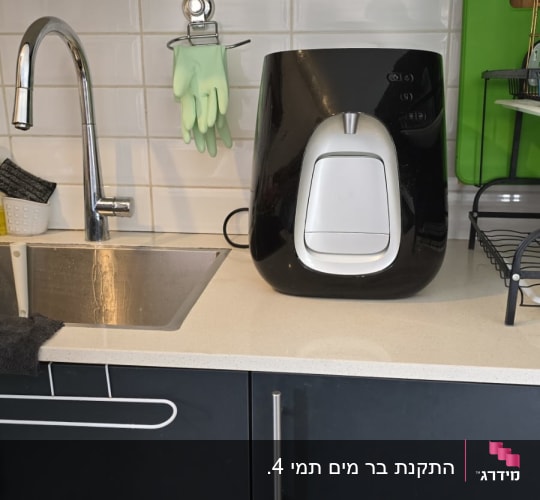 כיור מטבח עם ברז, כפפות גומי ומכשיר חשמלי על השיש